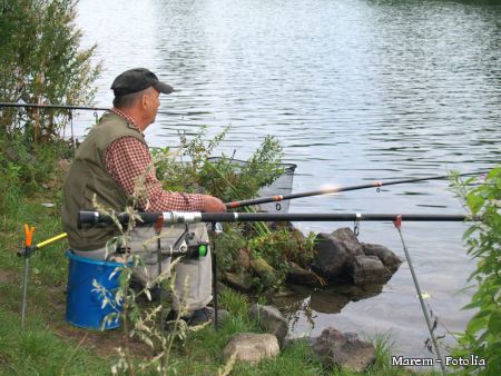 Mann sitzt am See und angelt