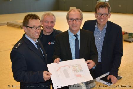 Der Kreis Paderborn betreibt in der Sporthalle des Berufskollegs Schloß Neuhaus eine Notunterkunft für Flüchtlinge: Polizeihauptkommissar Carsten Schlüter, Willi Schmidt (stellvertretender Vorsitzender des DRK Kreisverbandes Paderborn), Landrat Manfred Müller und Norbert Damke (Schulleiter des Berufskollegs Schloß Neuhaus) stellten gemeinsam Pläne und Konzepte vor (Foto:  Amt für Presse- und Öffentlichkeitsarbeit, Kreis Paderborn, Anna-Sophie Schindler)