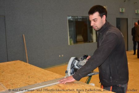 Seit Montag sind die Handwerker in der Sporthalle des Berufskollegs Schloß Neuhaus am Werkeln. Sie legen die Halle mit Holzboden aus und verkleiden die Wände, damit 200 Flüchtlinge dort untergebracht werden können. (Foto:  Amt für Presse- und Öffentlichkeitsarbeit, Kreis Paderborn, Anna-Sophie Schindler)