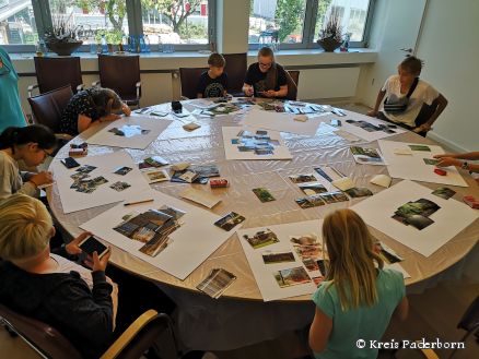 „Fotos werden zu Collagen zusammen gesetzt“: Der Runde Sitzungssaal im Kreishaus bot den Kulturrucksackkindern ausreichend Platz, ihre Fotoschätze auszubreiten 