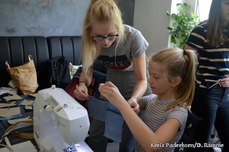 zu sehen ist eine Kursleiterin, die einer Teilnehmerin die Bedienung der Nähmaschine erklärt