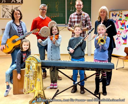Zu sehen sind vier Kinder der Grundschule mit verschiedenen Instrumente, die sie alle im Rahmen des Unterrichtes kennenlernen