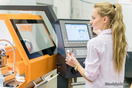 zu sehen ist eine junge Frau an einer CNC-Fertigungsmaschine
