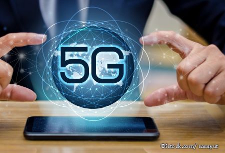 Ein Handy auf dem Tisch, darüber das Wort 5G in einer Blase