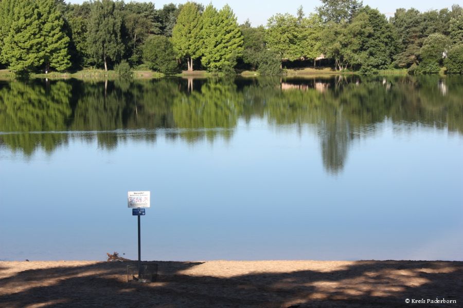 Still ruht hier beispielsweise auch der Habichtsee: Die Idylle trügt – unter der Oberfläche von Baggerseen lauern tödliche Gefahren. In 2013 ertrank hier ein 50-Jähriger  Vorn im Bild: Ein Wegweiser für die Rettungskräfte: Im Notfall die 112 wählen und dem Disponenten die Kennziffer nennen (Foto: Kreis Paderborn) Still ruht hier beispielsweise auch der Habichtsee: Die Idylle trügt – unter der Oberfläche von Baggerseen lauern tödliche Gefahren. In 2013 ertrank hier ein 50-Jähriger  Vorn im Bild: Ein Wegweiser für die Rettungskräfte: Im Notfall die 112 wählen und dem Disponenten die Kennziffer nennen (Foto: Kreis Paderborn)