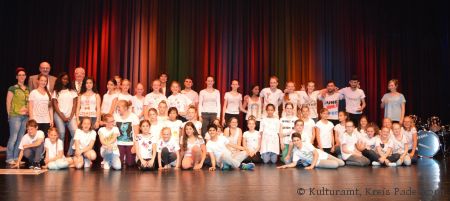 Diana Ramme, Kulturrucksack-Koordinatorin Kreis Paderborn, Wilhelm Beckmann, Vorsitzender des Kulturausschusses des Kreises Paderborn, Vinzenz Heggen, stellv. Landrat des Kreises Paderborn, (hintere Reihe-Mitte) Künstler Fabrice Jucquois mit den jungen Talenten der Gesamtschule Delbrück und der Luisenschule Bielefeld bei der Premiere von „Ich und ich“ in der Stadthalle Delbrück (Foto: Kulturamt, Kreis Paderborn)