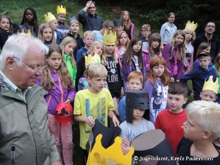 Von Rittern und Abenteuern im Jugendzeltlager des Kreisjugendamtes Paderborn: Friedhelm Kaup, Vorsitzender des Kreisjugendhilfeausschusses (ganz links im Bild), hört den Kindern aufmerksam zu (Foto: Jugendamt, Kreis Paderborn)