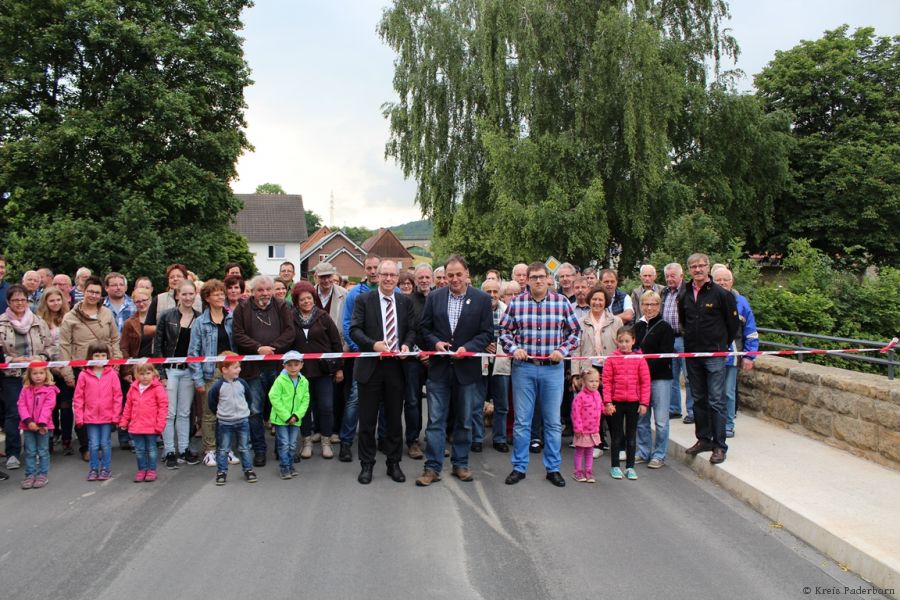 Ein ganzes Dorf feiert: - vorn im Bild, von links nach rechts, Landrat Manfred Müller, Ortsvorsteher von Weine, Norbert Steven, Christian Gehle, Mitarbeiter des Kreisstraßenbauamtes freuen sich mit Weine über die Freigabe der Brücke (Foto: Kreis Paderborn)
