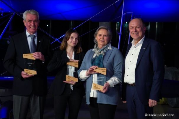 Landrat Christoph Rüther beim Start ins Jahr 2023 des Kreises Paderborn mit den Ehrenamtspreisträgern 2022 vor einem blauen Hintergrund im Quax-Hangar beim Flughafen Paderborn-Lippstadt